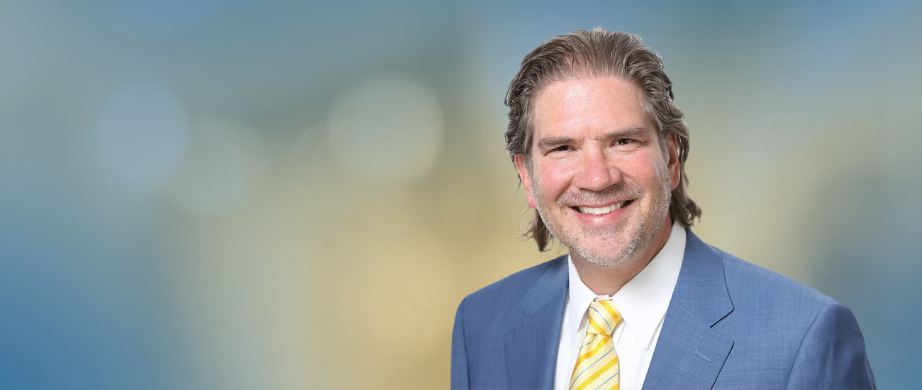 Professional headshot of Travis R. Hollifield against a blurred background